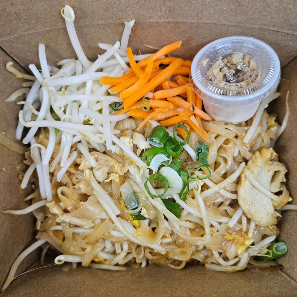 Easy Thai Bend's Pad Thai with noodles, chicken, bean sprouts, carrots, and green onions in a takeout box.