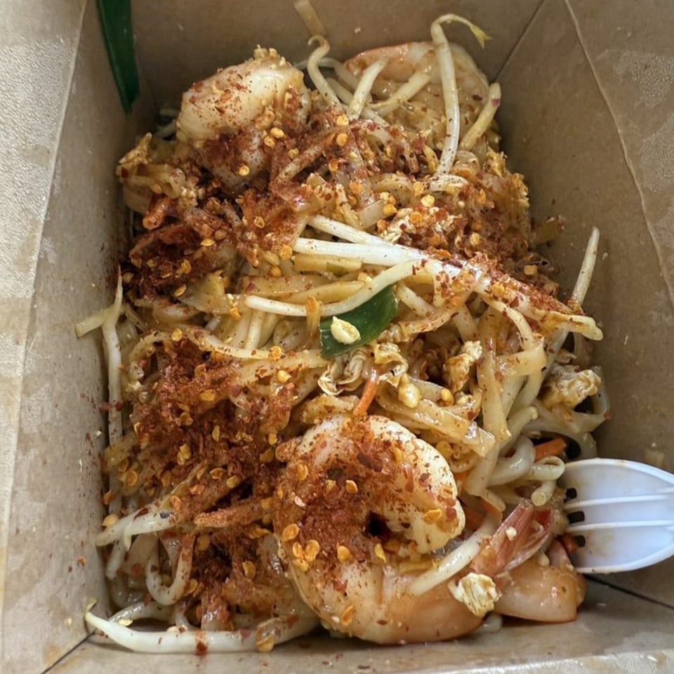 Easy Thai Bend's shrimp Pad Thai with noodles, bean sprouts, and chili flakes in a takeout box.